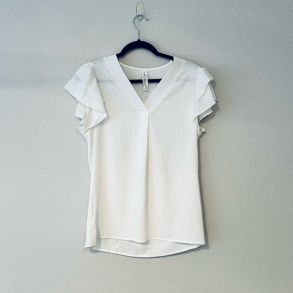 White v-neck medium blouse with ruffled short sleeves.